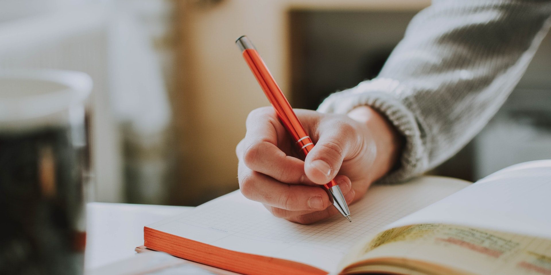 person-holding-orange-pen-1925536